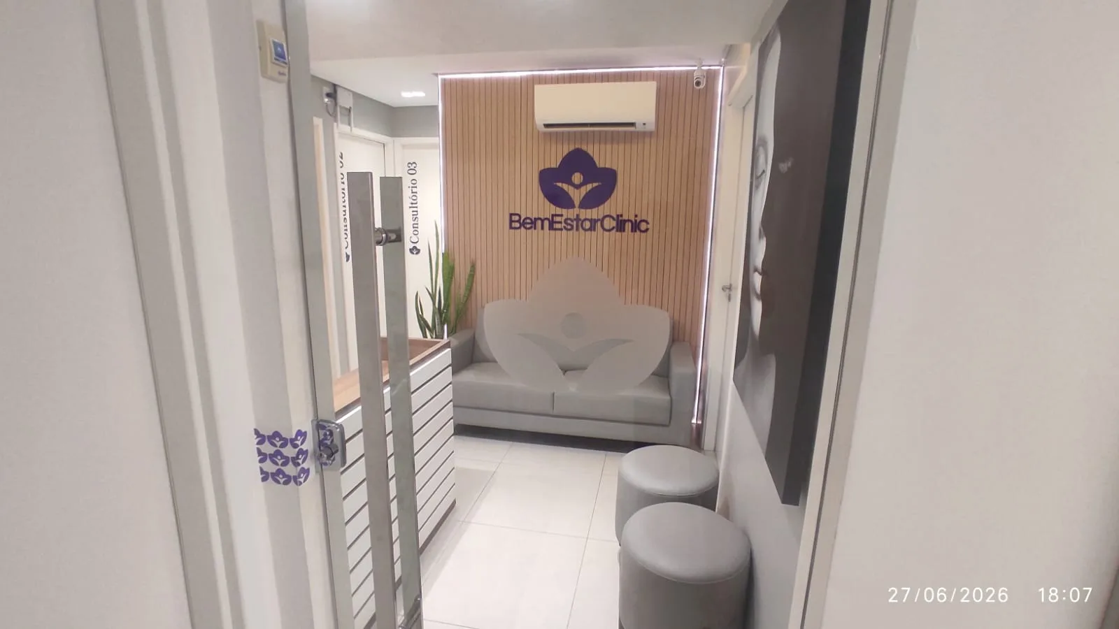 Recepção da BemEstarClinic, com a marca na parede de ripas de madeira e o corredor dos consultórios
